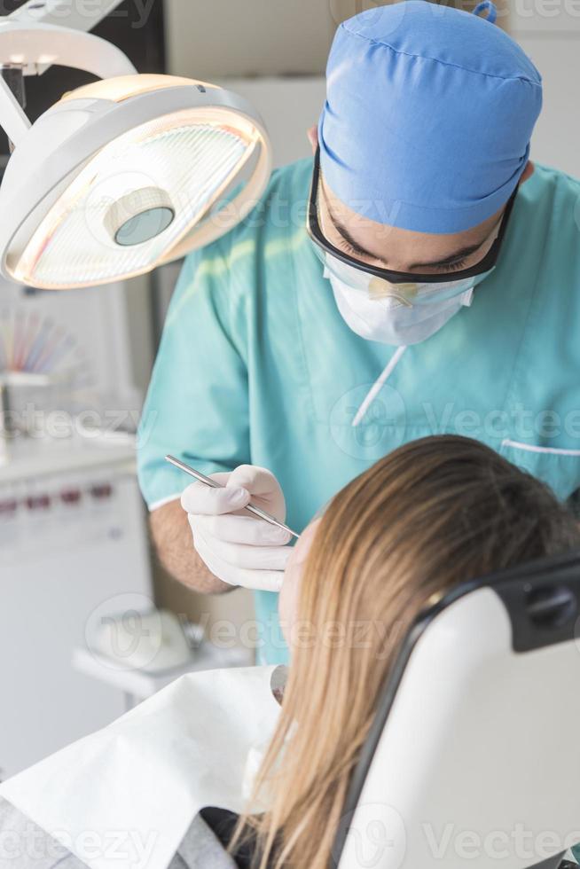 tandläkare härdning patientens tänder fyllning hålighet. tandläkare arbetssätt med professionell Utrustning i klinik. foto