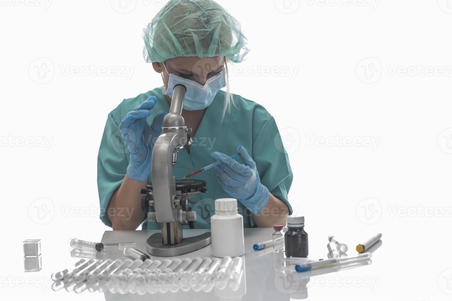 forskare i blå medicinsk handskar och enhetlig inlärning covid-19 prover med mikroskop i laboratorium. foto