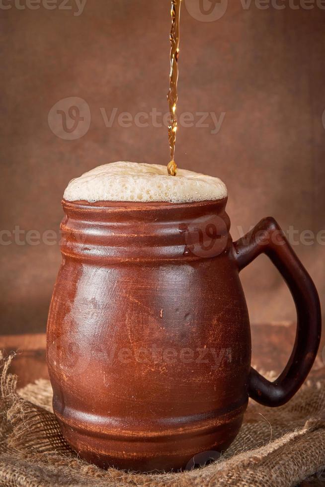 öl lera brun råna med kvass på en trä- tabell på en mörk bakgrund. en traditionell dryck tillverkad av bröd, surdeg foto