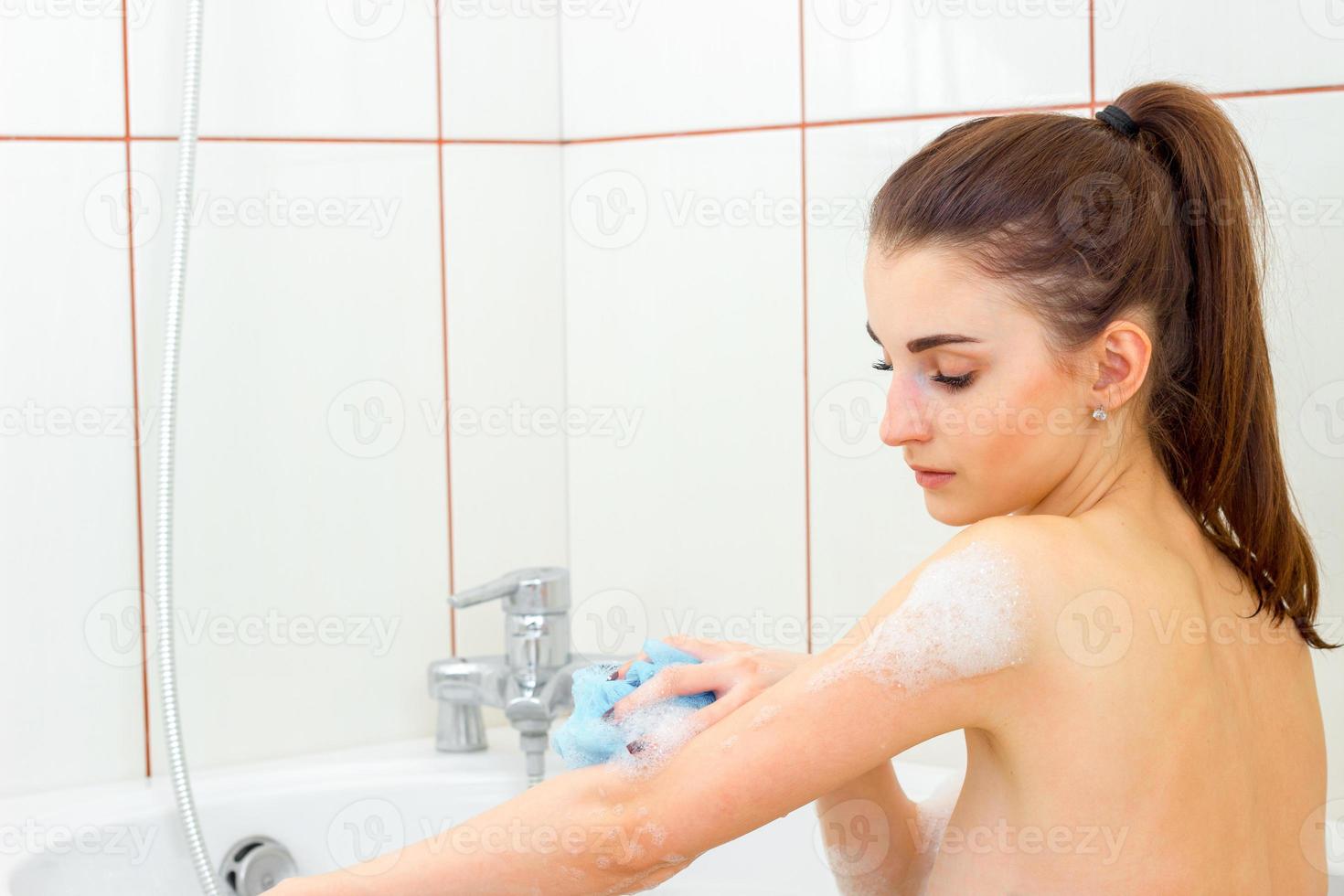 ung våt kvinna i tvålar är badade i en bad foto