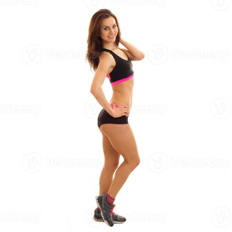 ung attraktiv atletisk flicka i svart topp och shorts Framställ på kamera foto