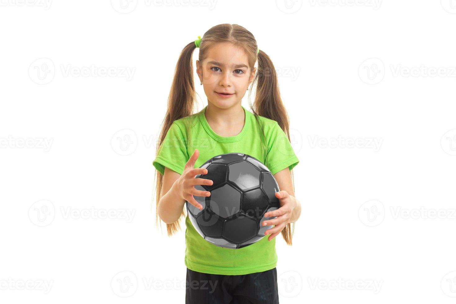 charmig liten flicka i grön skjorta med fotboll boll i händer foto