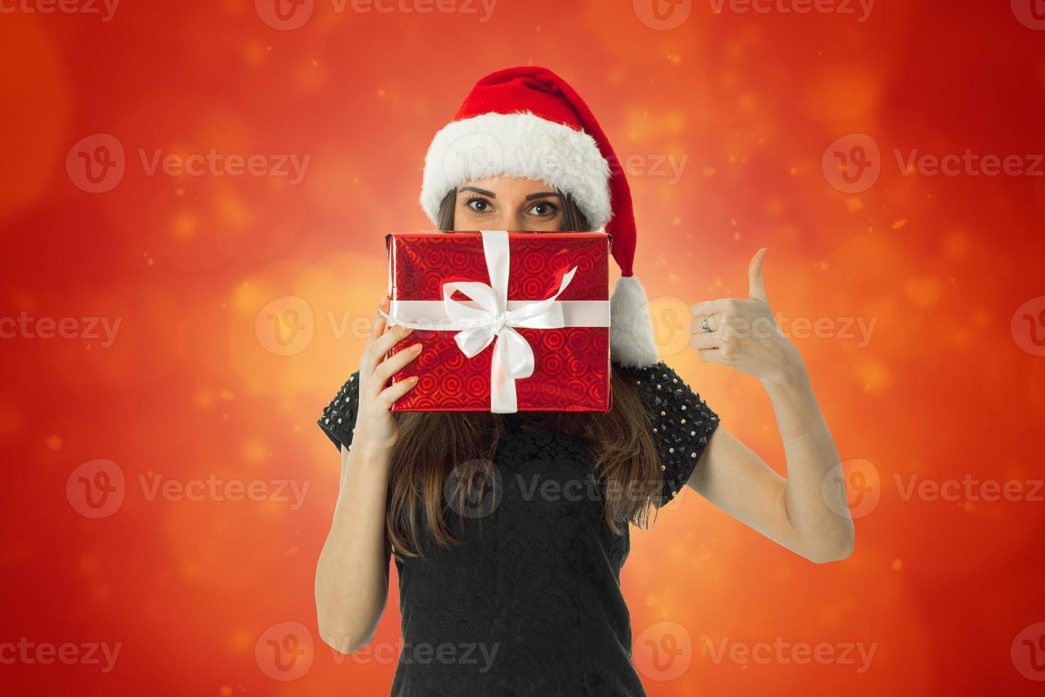 kvinna i santa hatt med röd gåva foto