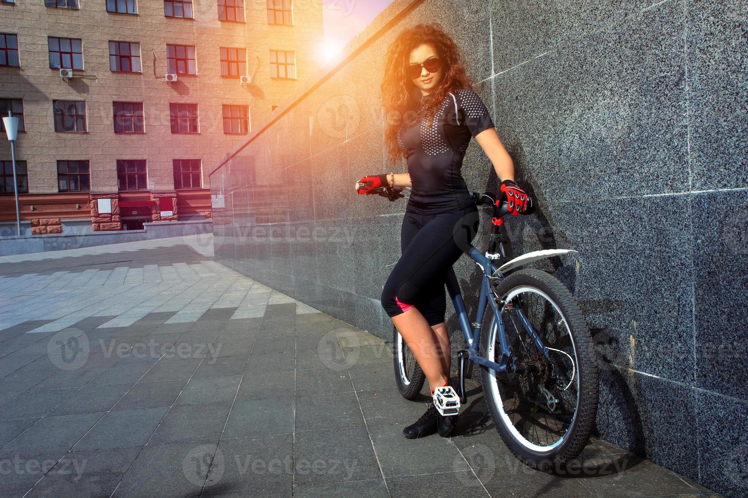 skön ung kvinna med lockigt röd hår på cykel foto