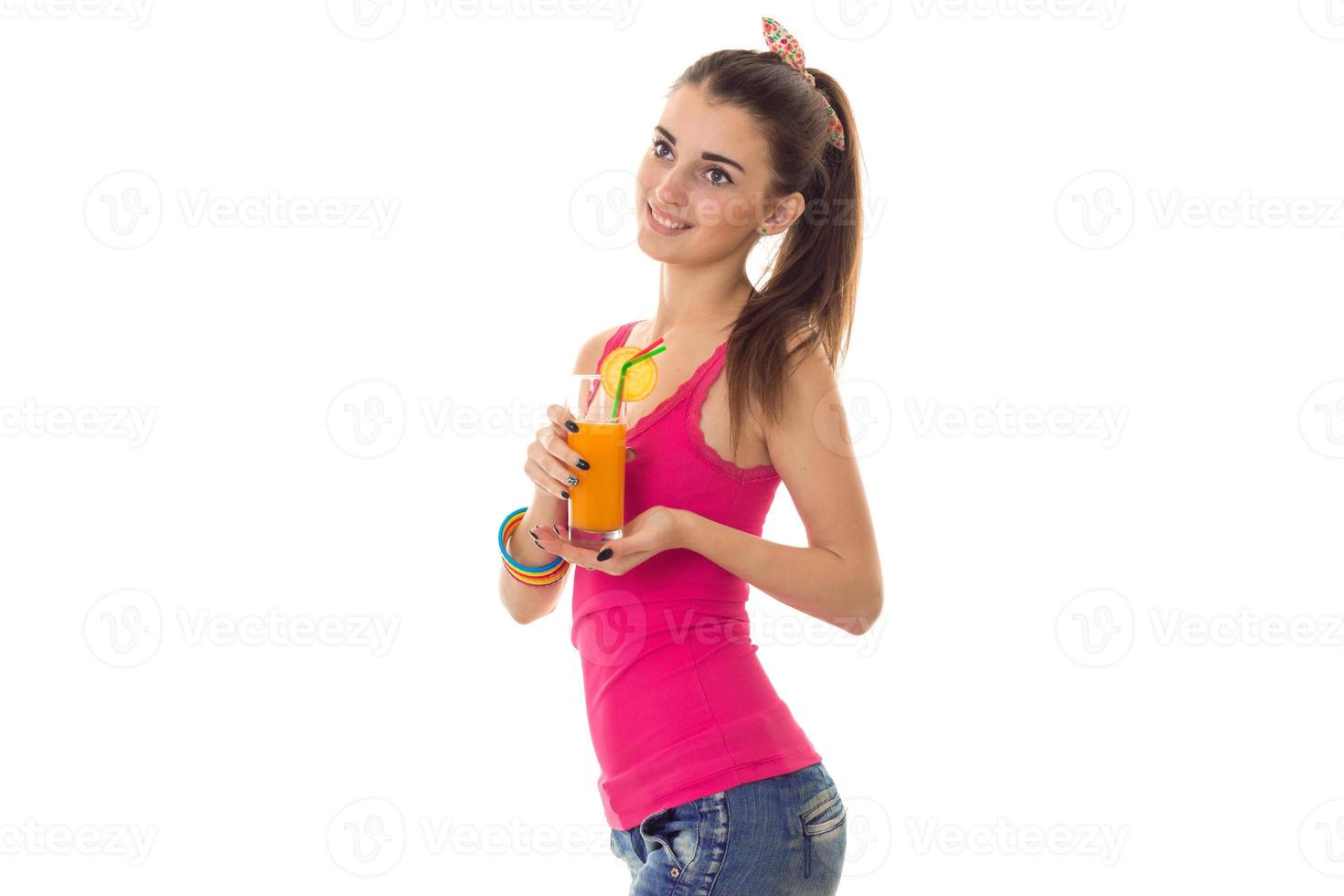 Lycklig ung flicka i rosa skjorta leende och dricka ett orange cocktail isolerat på vit bakgrund foto