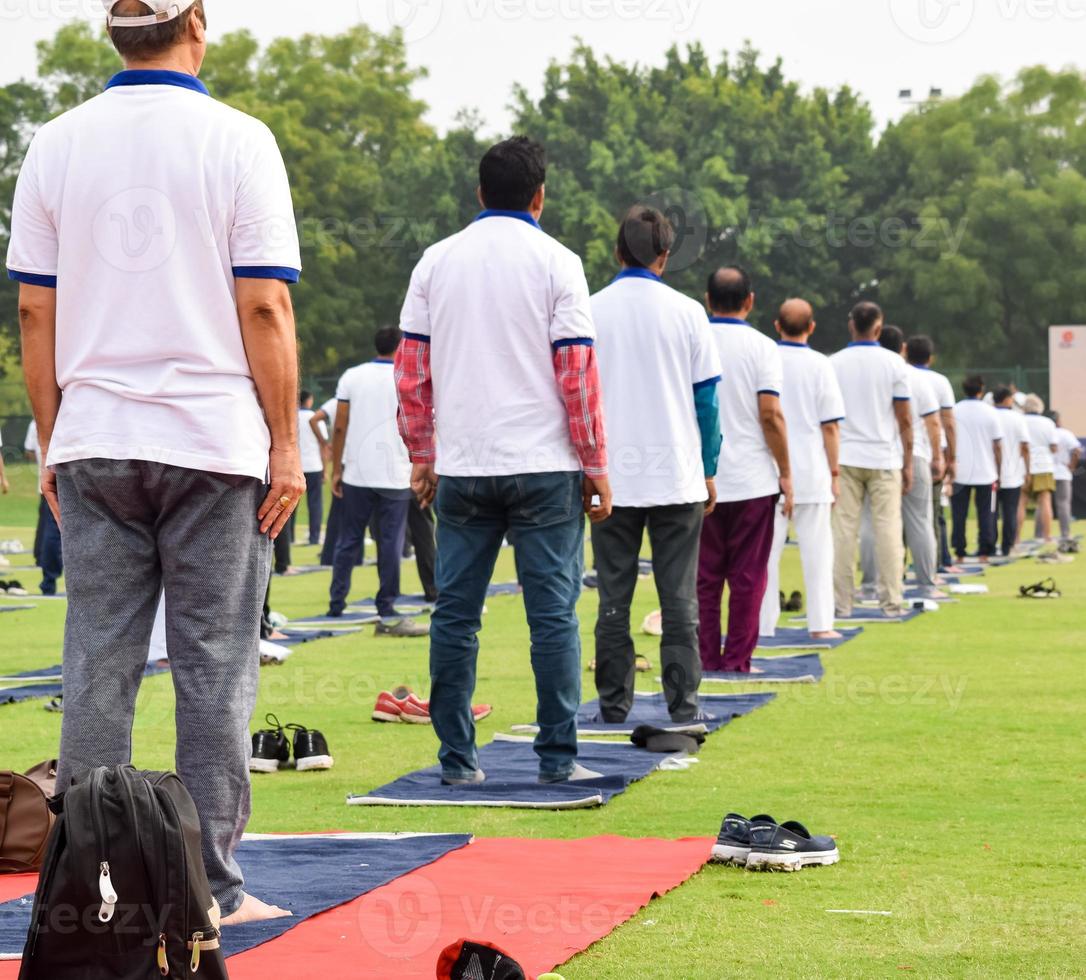 grupp yoga övning session för människor av annorlunda ålder grupper på cricket stadion i delhi på internationell yoga dag, stor grupp av vuxna delta yoga session foto