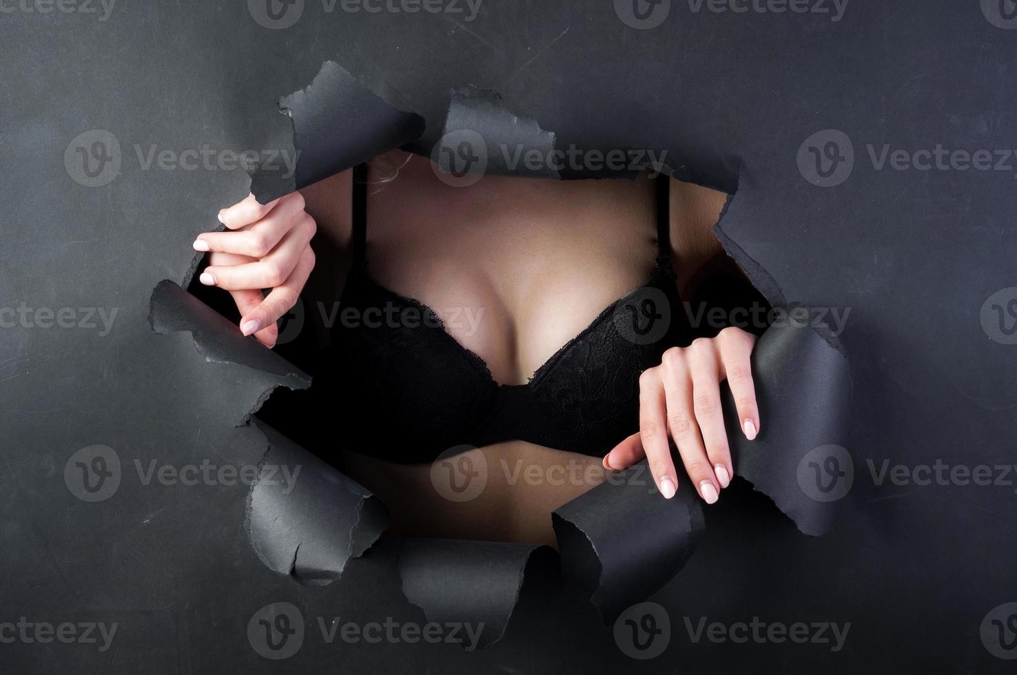 en kvinnas bröst utbuktning ut av en trasig svart bakgrund. foto