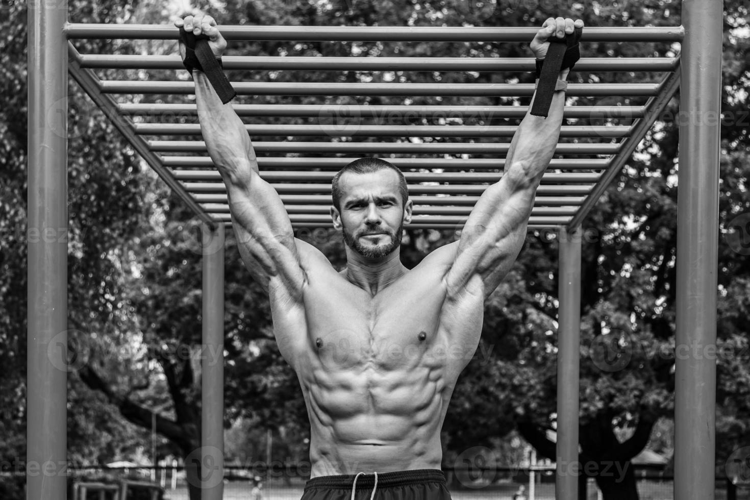 muskulös man håller på med pull-ups på horisontell bar foto