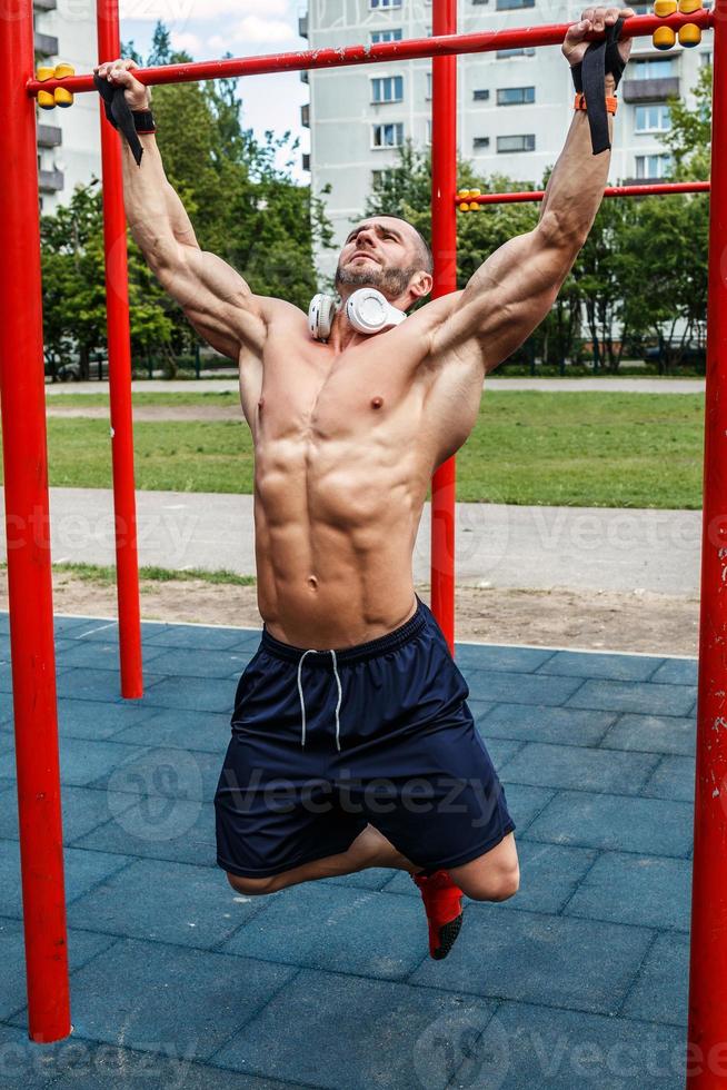 muskulös man håller på med pull-ups på horisontell bar foto