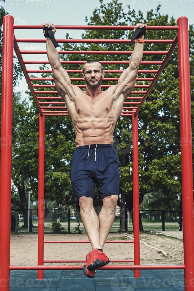 muskulös man håller på med pull-ups på horisontell bar foto