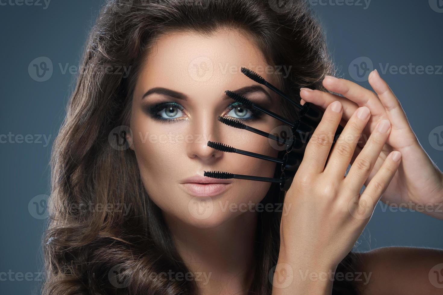 skön kvinna applicering mascara på henne fransarna foto