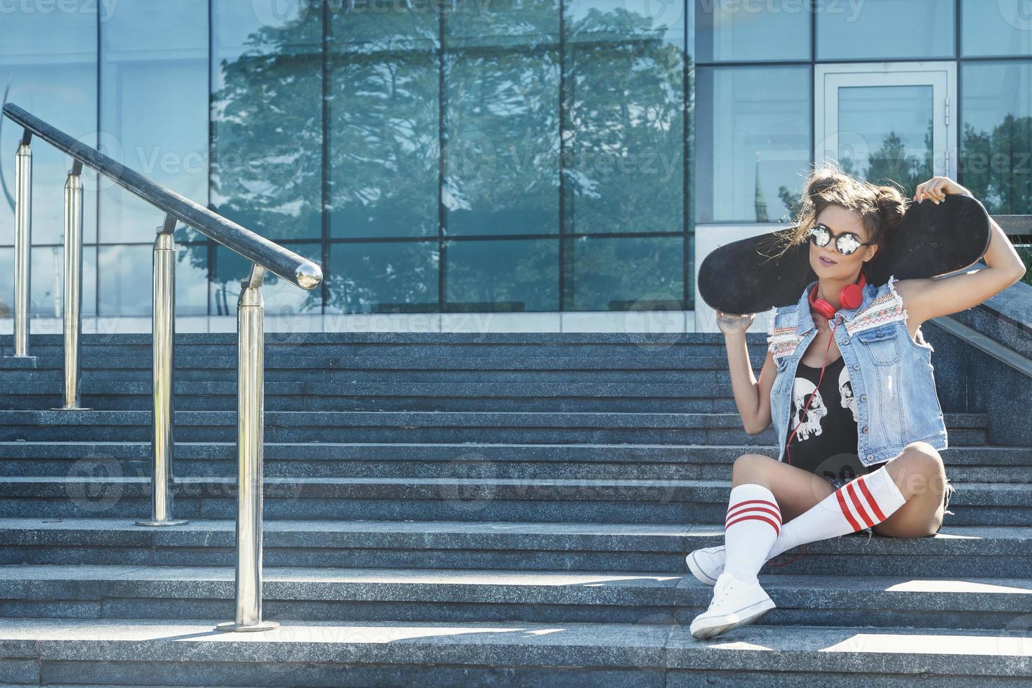 eleganta flicka med en skateboard på de gata foto