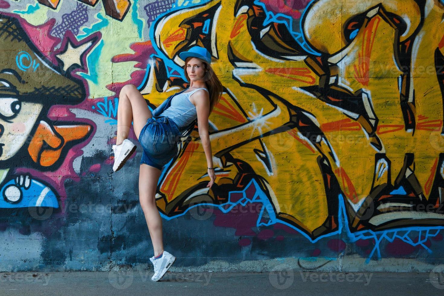 flicka i denim overall Framställ mot vägg med graffiti foto