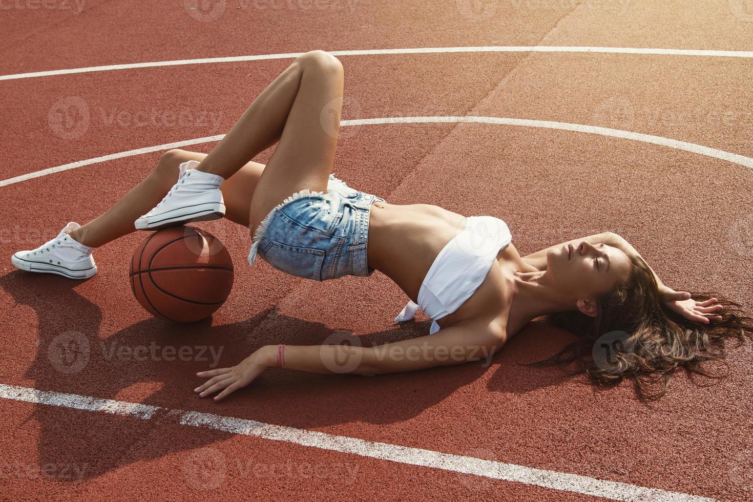 ung sexig kvinna med på en basketboll lekplats foto