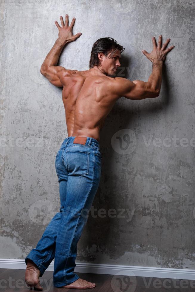 porträtt av stilig muskel man bär blå jeans foto
