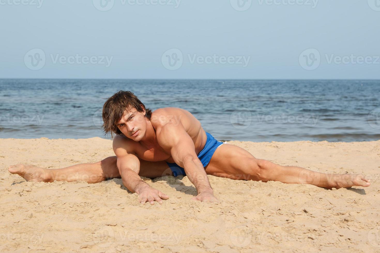 muskulös man under hans träna på de strand foto