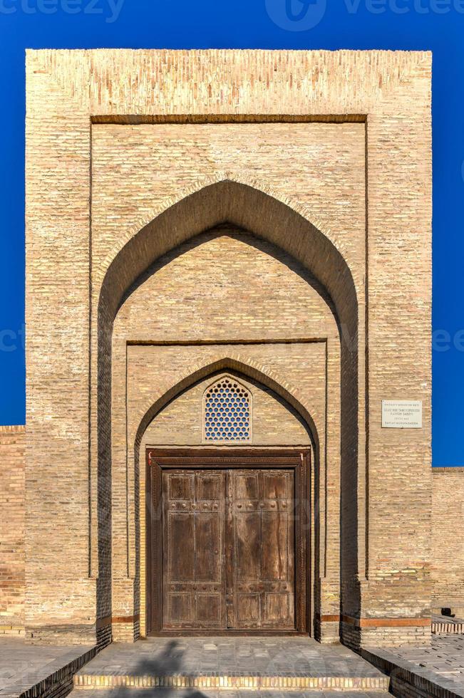 Fasad av de gammal karavanseraj ulugbek tamokifurush, 19:e århundrade, med ristade trä- dörr i bukhara, uzbekistan. foto