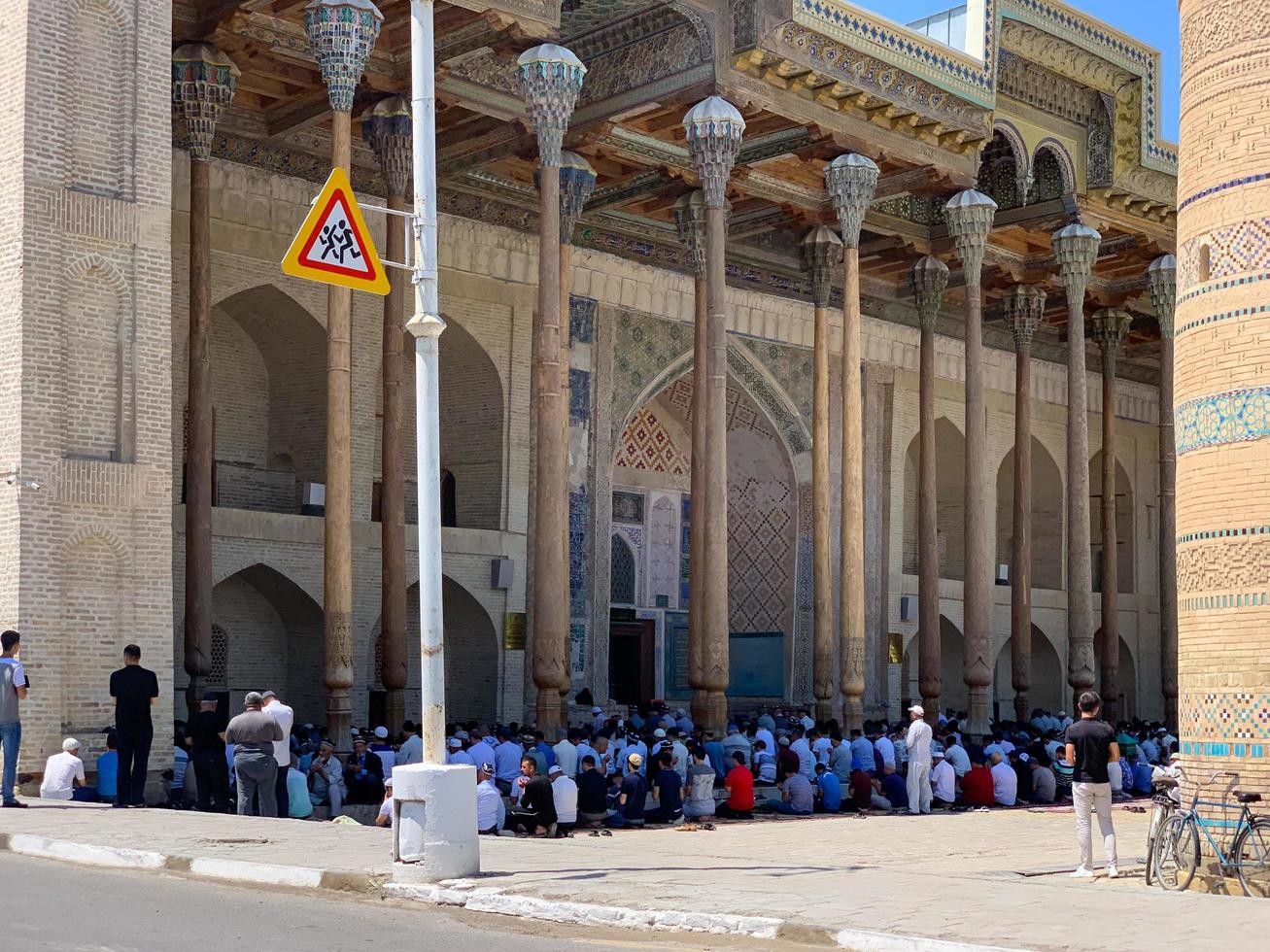 bukhara, uzbekistan - juli 12, 2019 - svar de ring upp av bön på bolo-hauz moské, byggd i de 17:e århundrade, med trä- ristade kolonner i bukhara, uzbekistan. foto