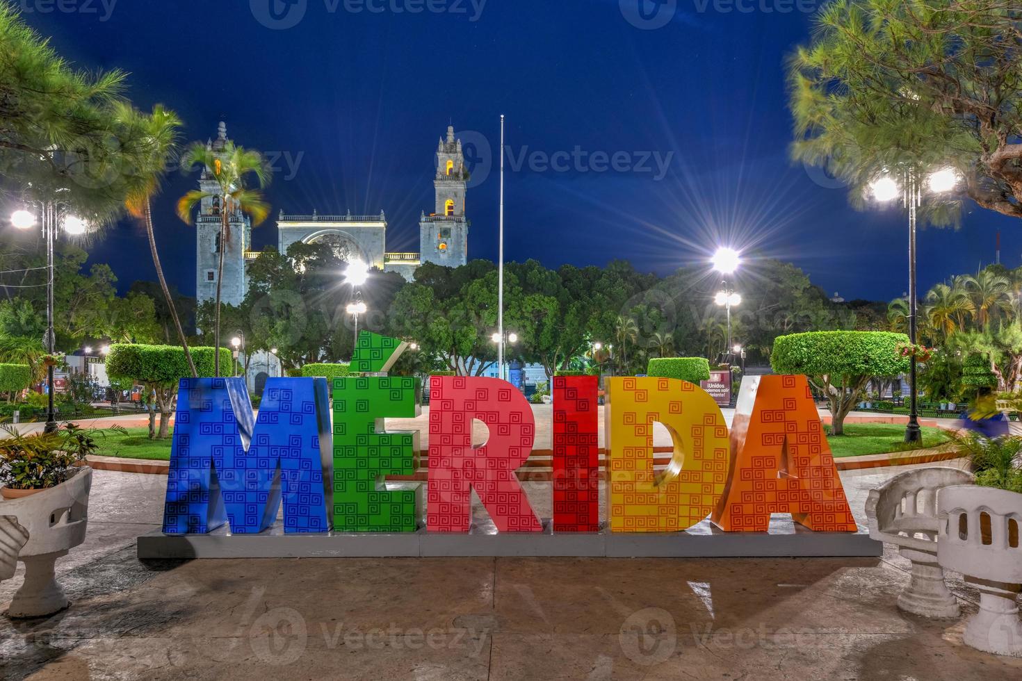 stor färgrik brev representerar merida med ett ikoniska merida katedral på de bakgrund på natt. foto
