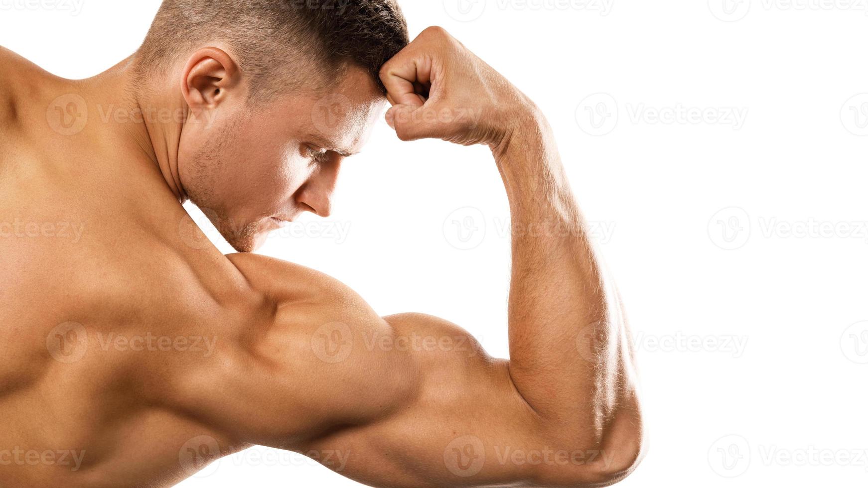 ung muskulös man som visar hans bicep på vit foto