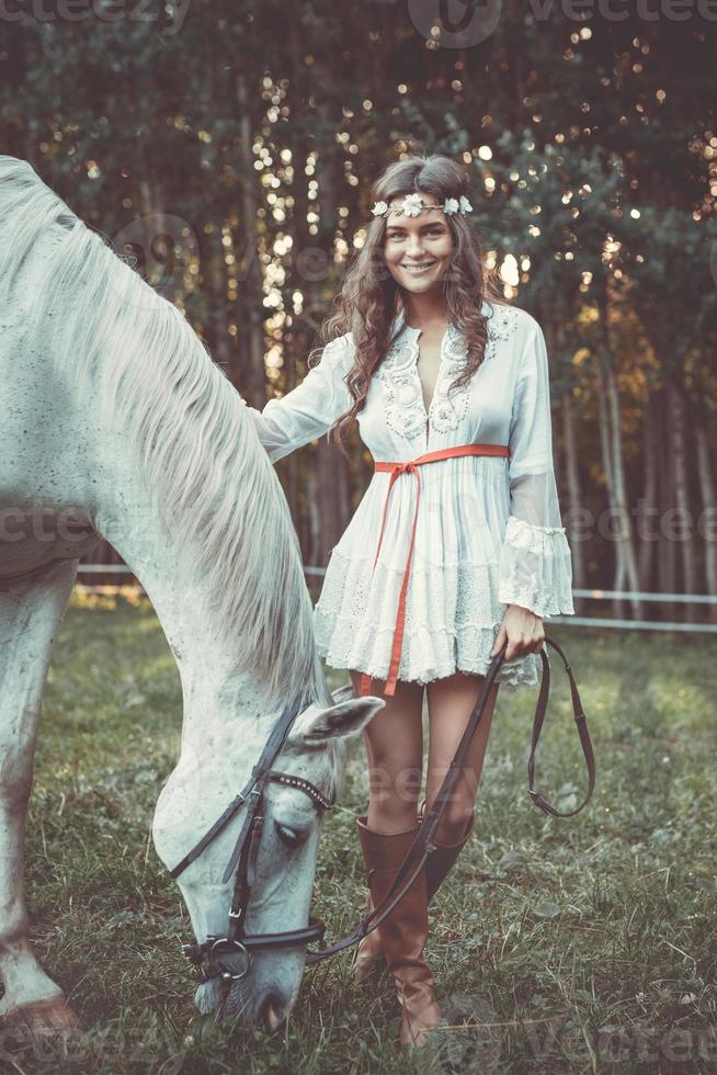 ung kvinna i skön vit klänning och henne skön häst foto