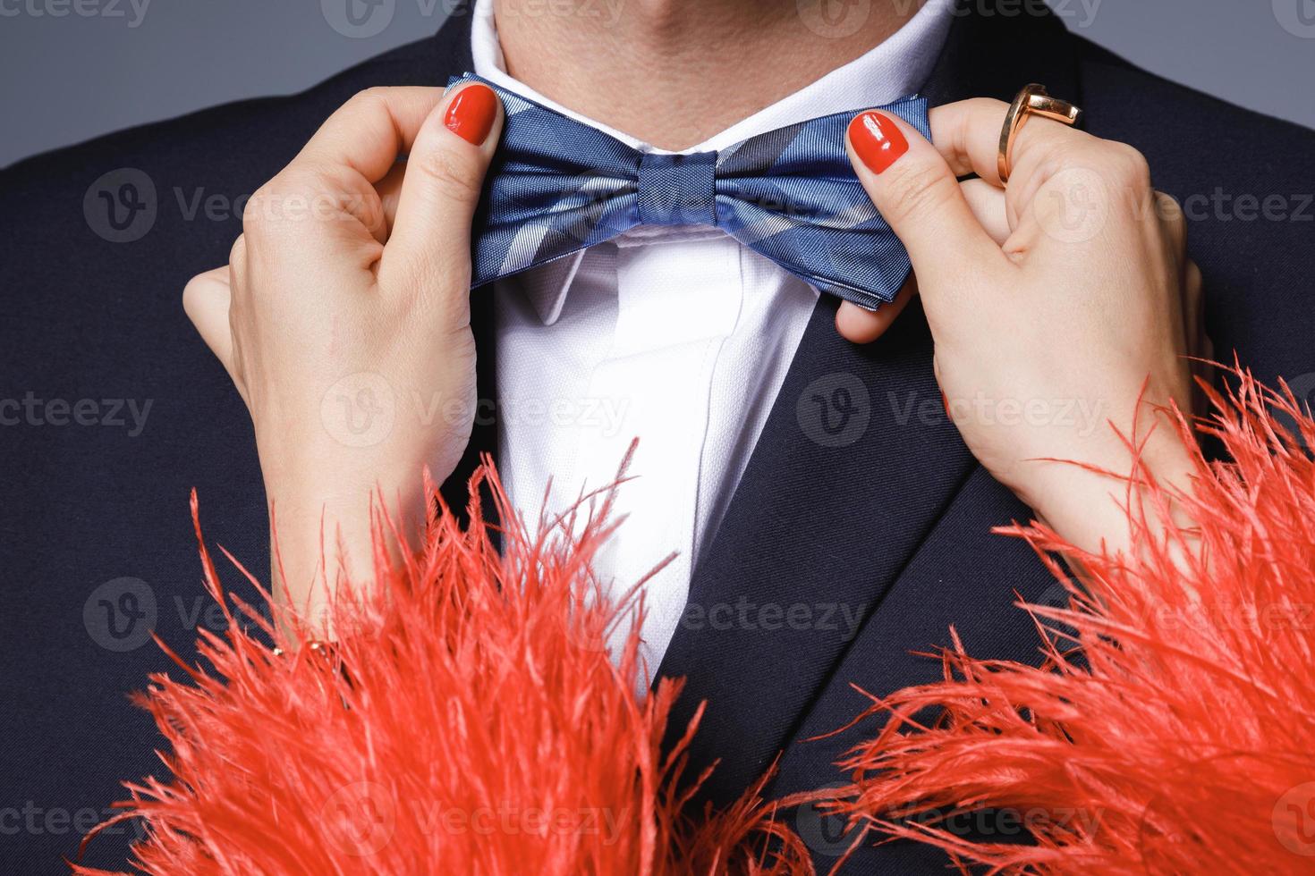 kvinna är portion till passa upp en rosett slips till henne man foto
