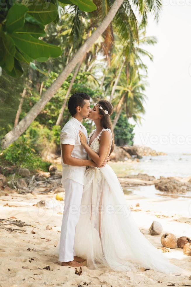 ung och skön par är fira bröllop på de strand foto
