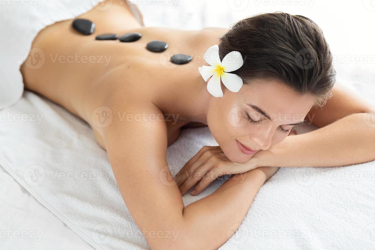 ung och skön kvinna under varm stenar massage foto