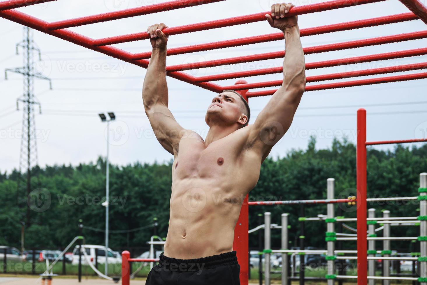 muskulös man håller på med pull-ups på horisontell bar foto