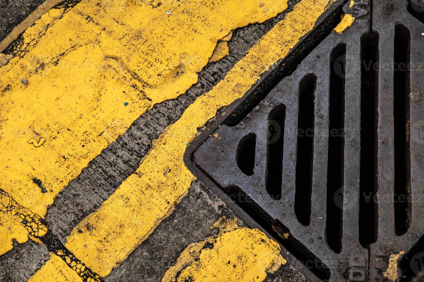 storm dränera och gul väg markeringar på de gammal asfalt foto