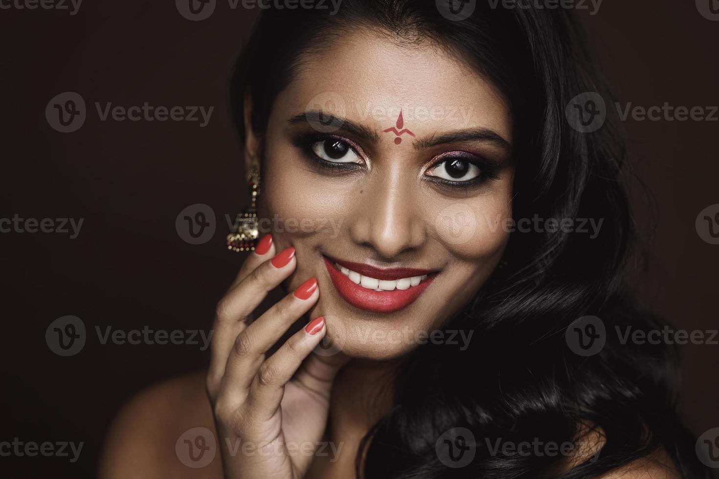 porträtt av indisk kvinna med skön smink och frisyr på brun bakgrund foto