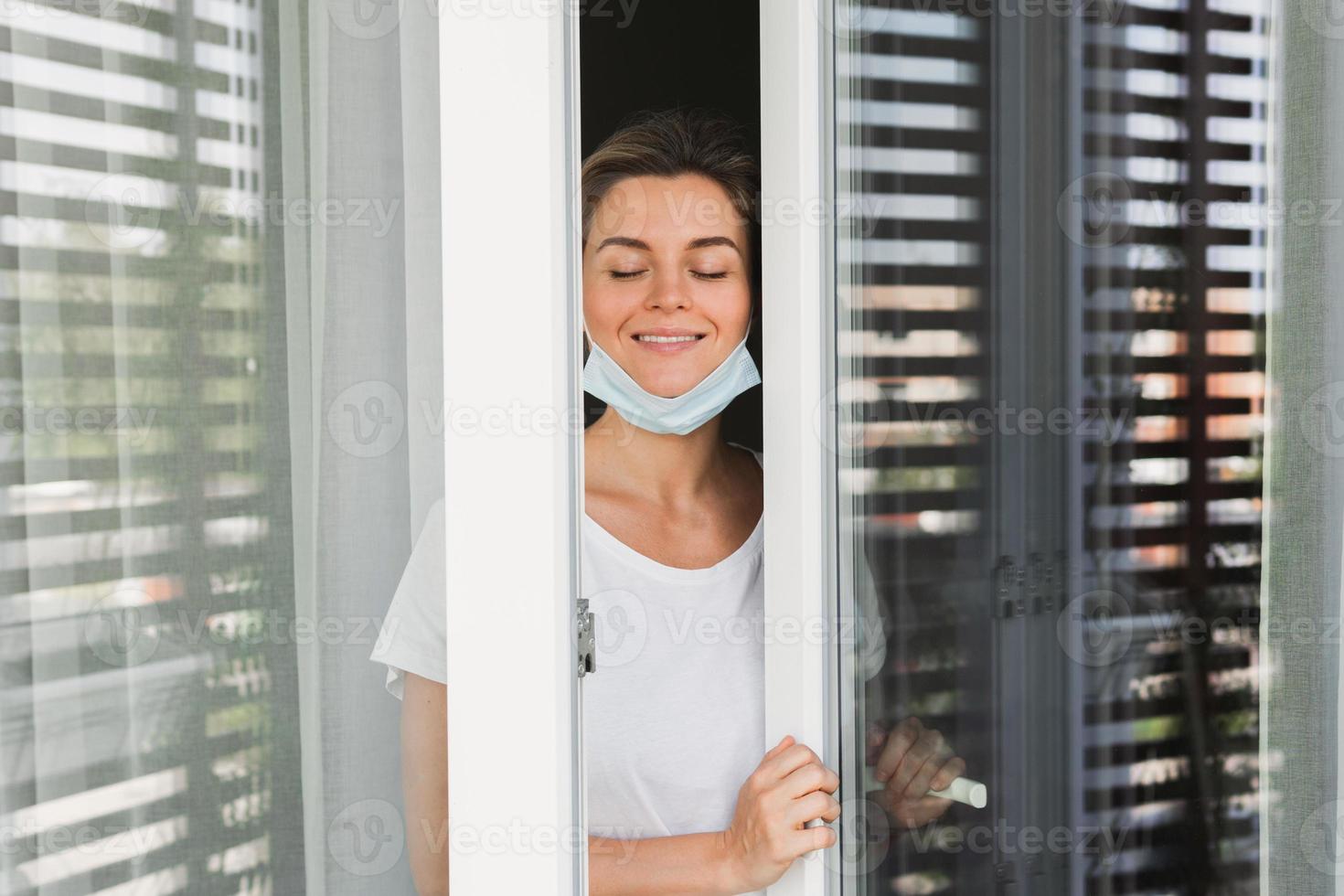 kvinna är gående på en balkong till ta en djup andetag eftersom var använder sig av förebyggande mask foto