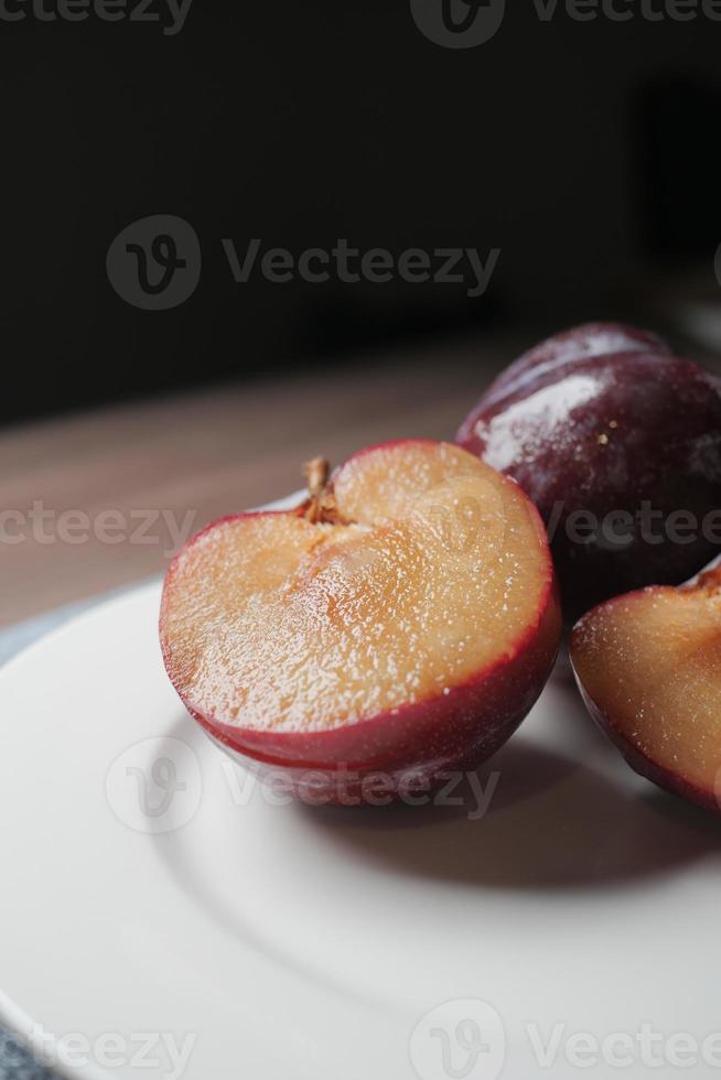 skivad färsk röd plommon frukt på en trä- tabell foto