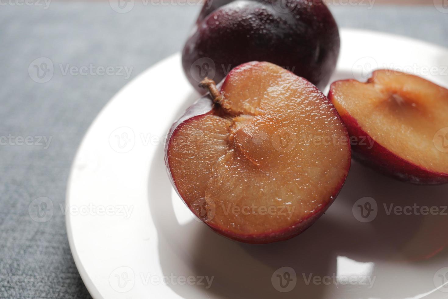 skivad färsk röd plommon frukt på en trä- tabell foto