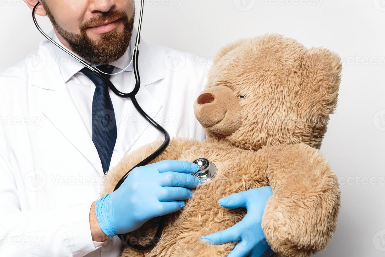 professionell barnläkare med en teddy Björn i hans händer foto