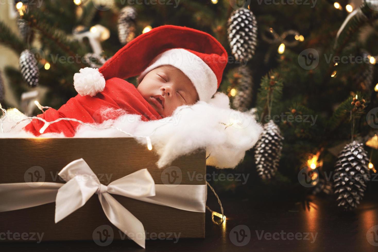 söt nyfödd bebis bär santa claus hatt är sovande i de jul gåva låda foto