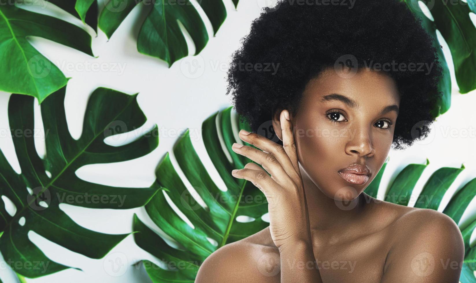 ung och skön afrikansk kvinna med perfekt slät hud i tropisk löv foto