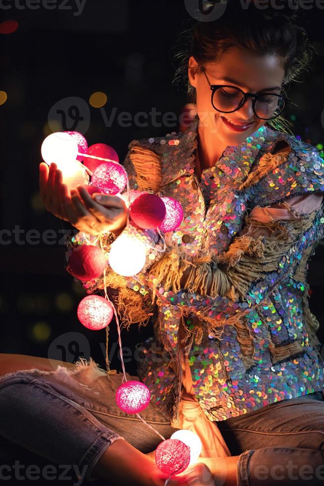 Lycklig kvinna bär lysande jacka med paljetter är innehav ljus bollar i henne händer foto