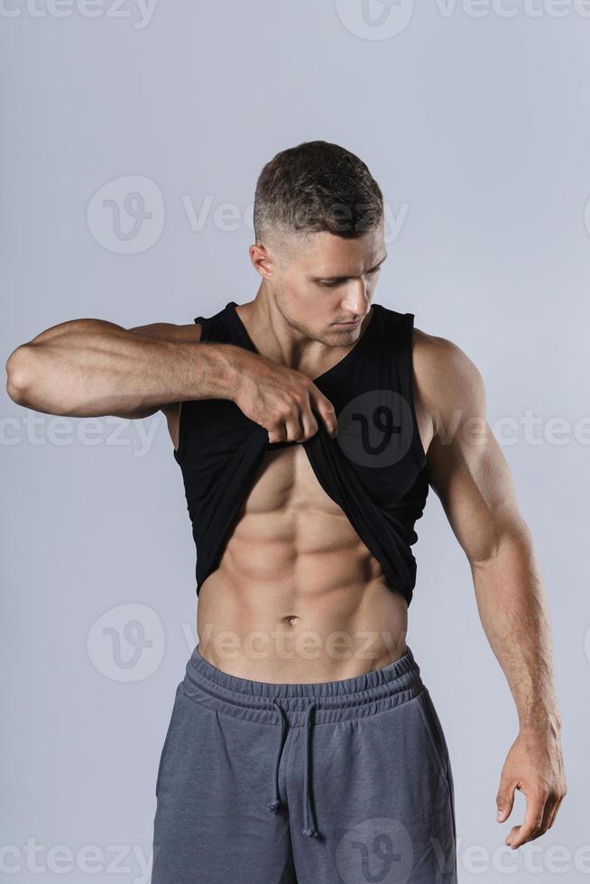 ung kroppsbyggare som visar hans muskulös kropp mot grå bakgrund foto