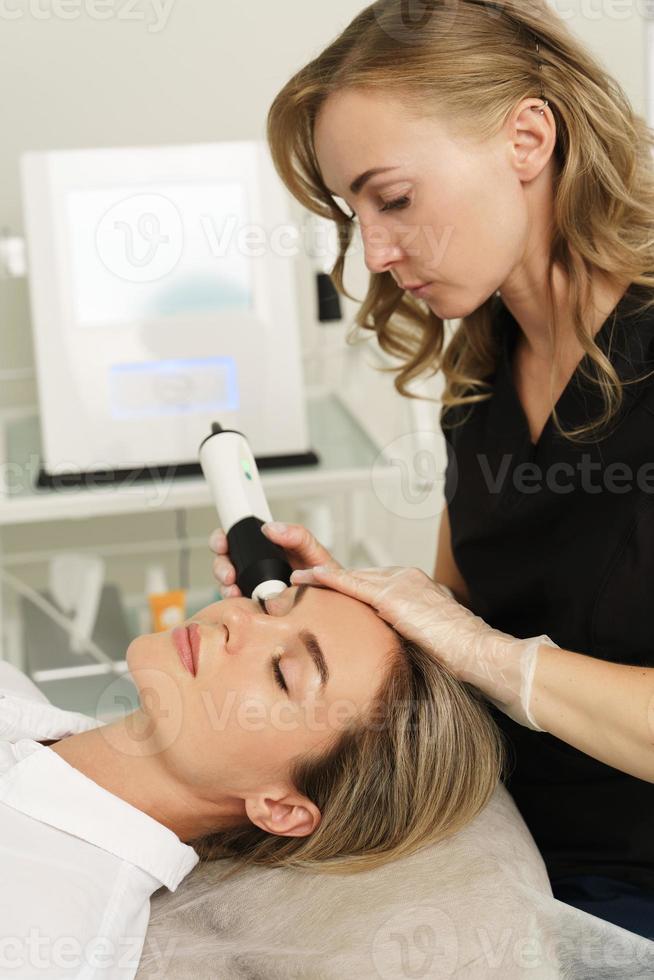 kvinna under kol dioxid laser återytas i en kosmetologi klinik foto