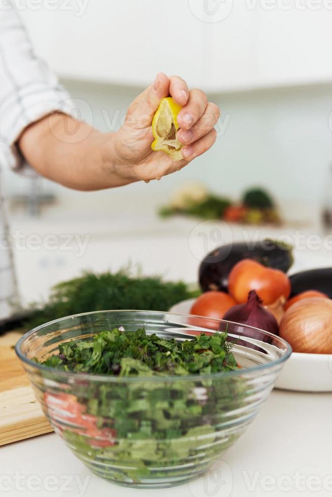 kvinna händer klämma och tillsats citron- juice till vegetarian sallad foto