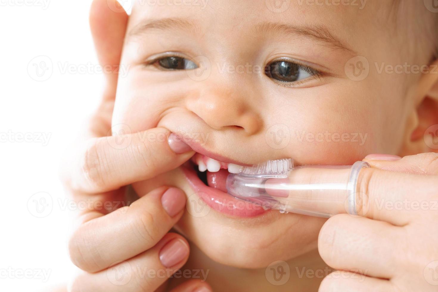 mor försiktigt borsta henne små barn tänder. foto