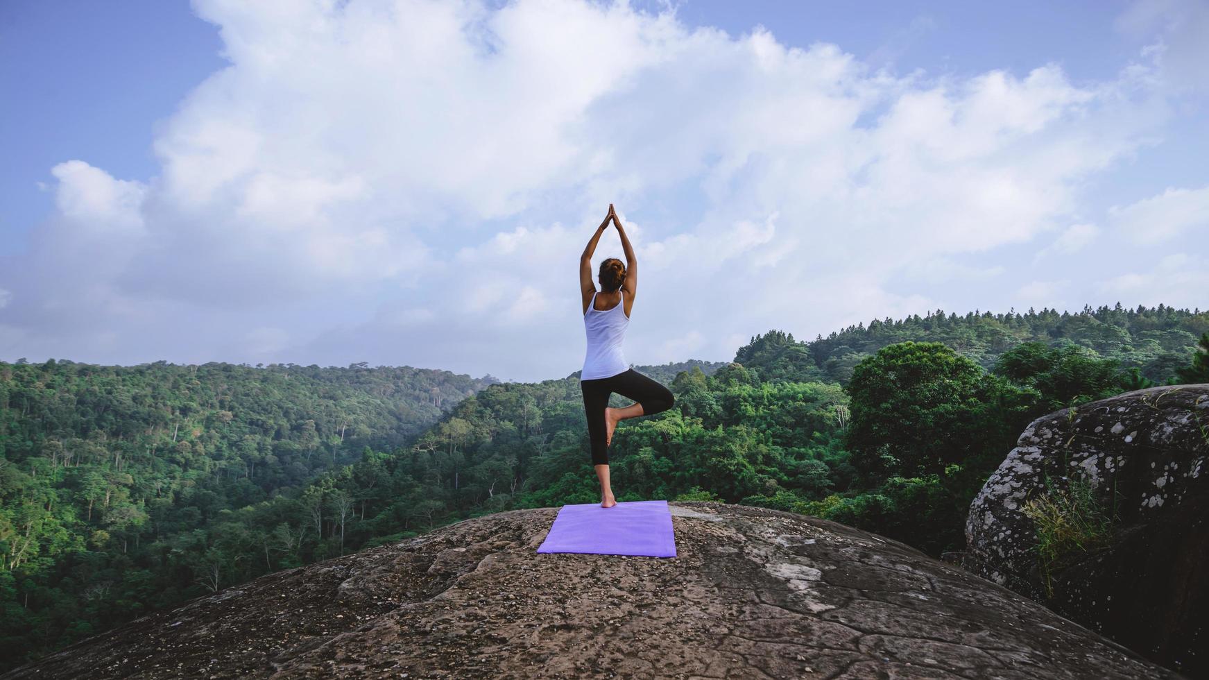 asiatiska kvinnor koppla av i semestern. spela om yoga. på bergsklippan. natur bergsskogar i thailand. ung kvinna utövar yoga i naturen kvinnlig lycka. träna yoga foto