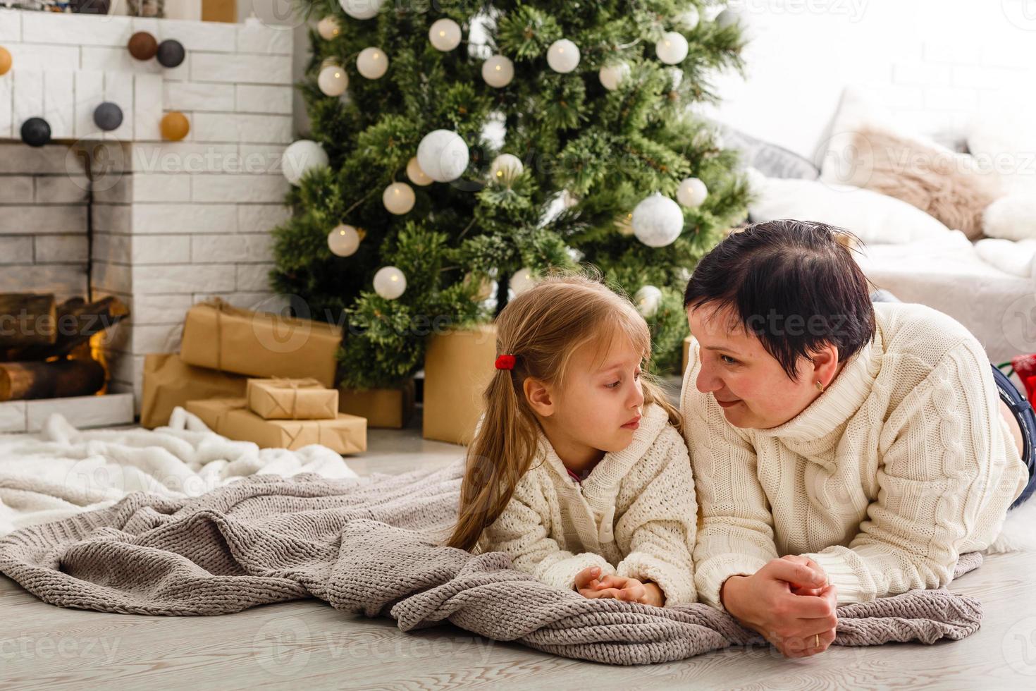 mor och dotter uppackning en närvarande liggande på de golv i de levande rum foto