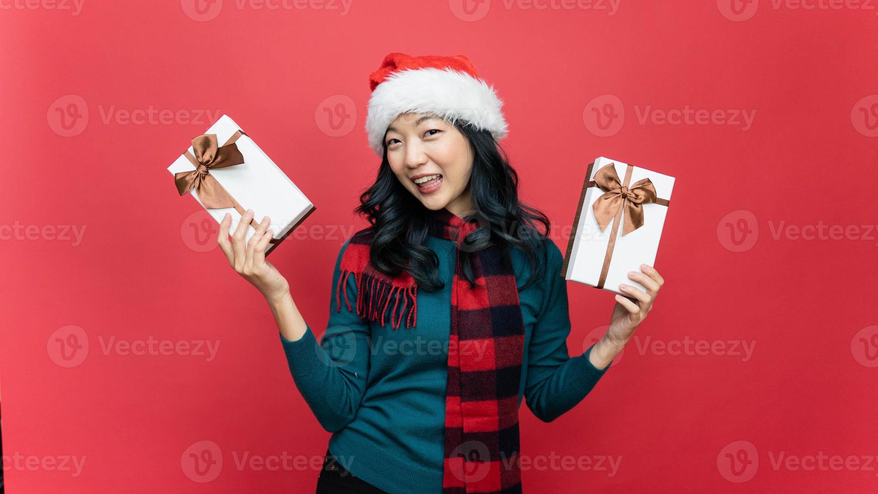 Lycklig lady i santa hatt innehav jul närvarande isolerat över röd bakgrund. begrepp av de ny år och jul dag. foto