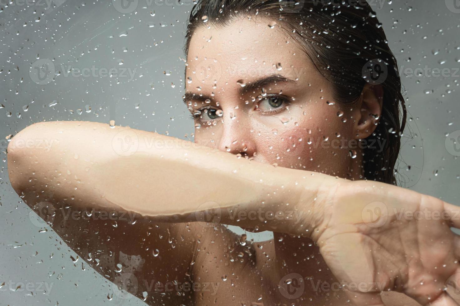 porträtt av sensuell kvinna fångad genom våt glas foto