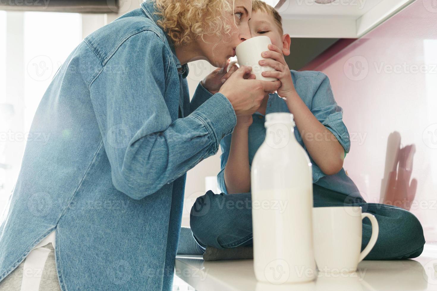 mor och henne söt son dricka mjölk på de kök foto