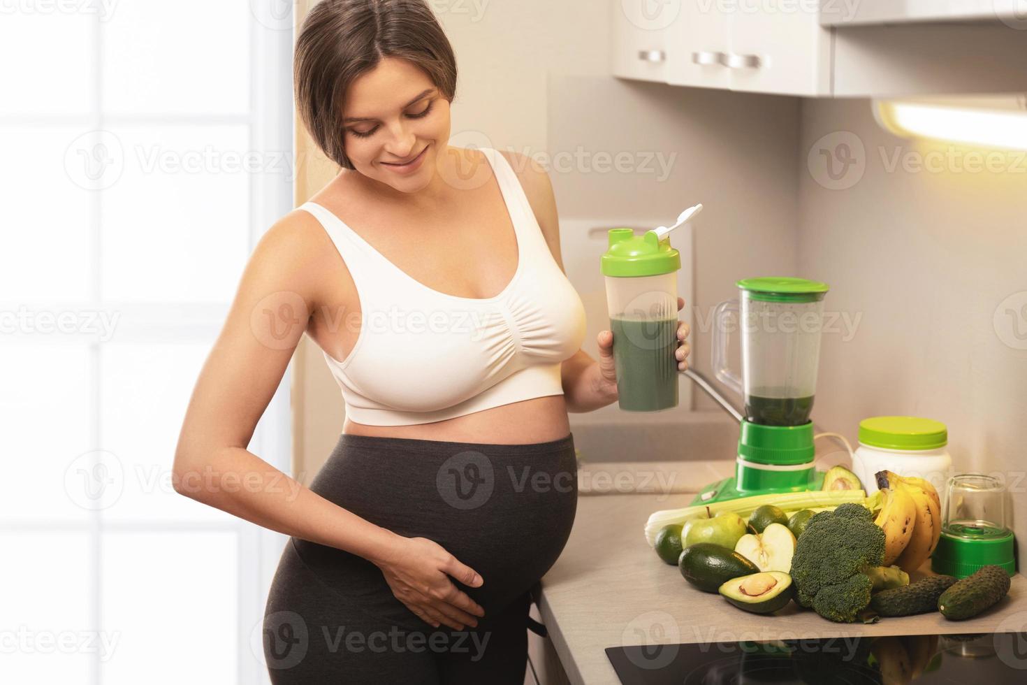 gravid kvinna innehav shaker med en grön protein cocktail foto