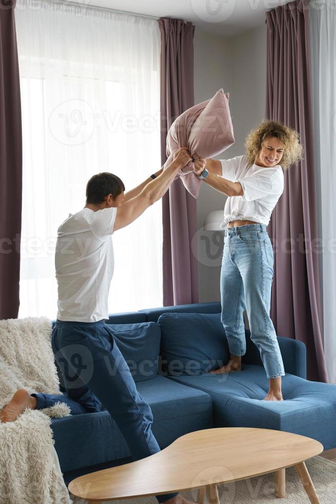 Lycklig par under kudde bekämpa i deras lägenhet foto