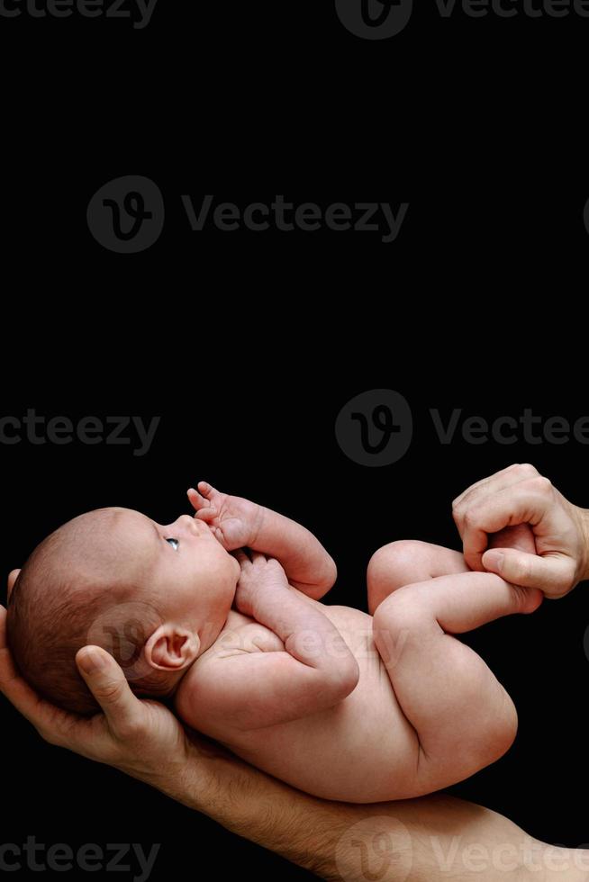söt nyfödd bebis liggande i de fars händer foto
